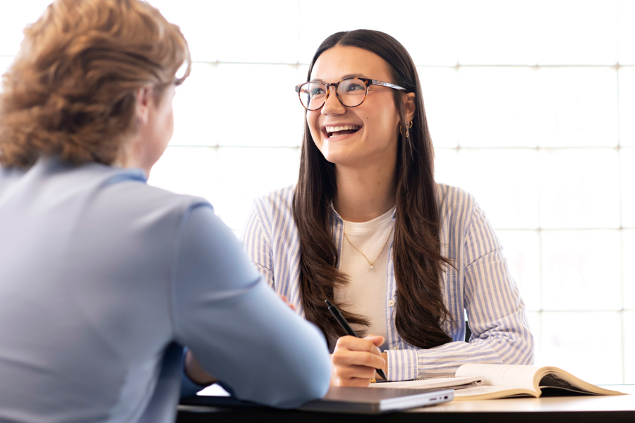 Two students interested in Women's and Gender Studies meet in a well-lit room with glass bricks