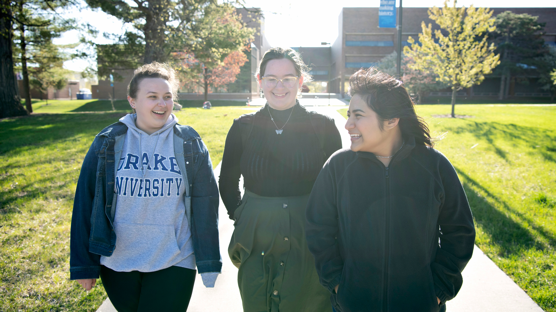 Three students studying Women's and Gender Studies at Drake walk through campus on a sunny yet windy day