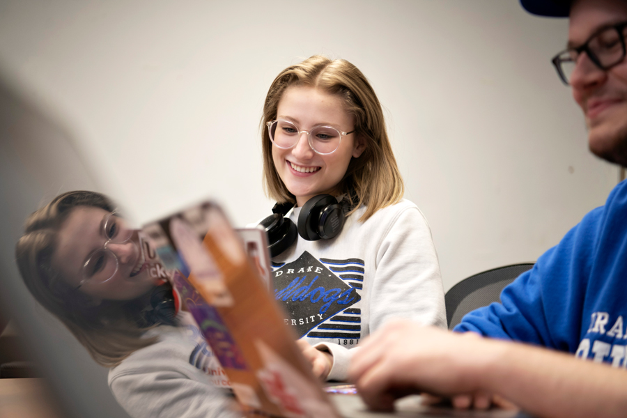 A student wearing headphones looks down at their laptop during a class for Drake's Women's and Gender Studies Concentration
