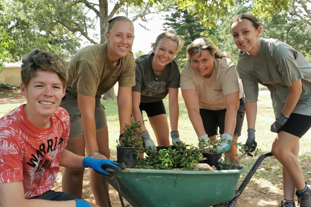 Students from Drake's Zoo and Conservation Science program stand around a wheelbarrow as they plant outdoors