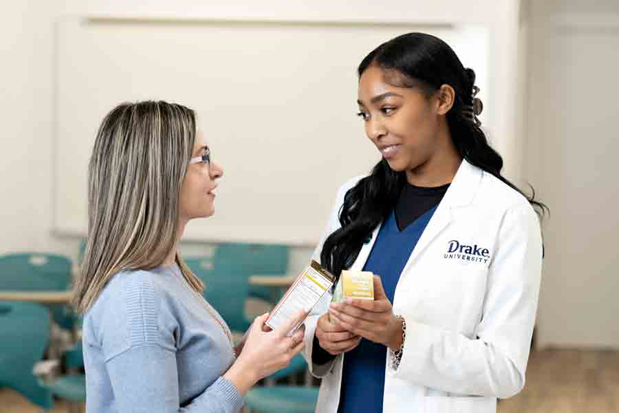 Two individuals look at medication boxes in a medical setting