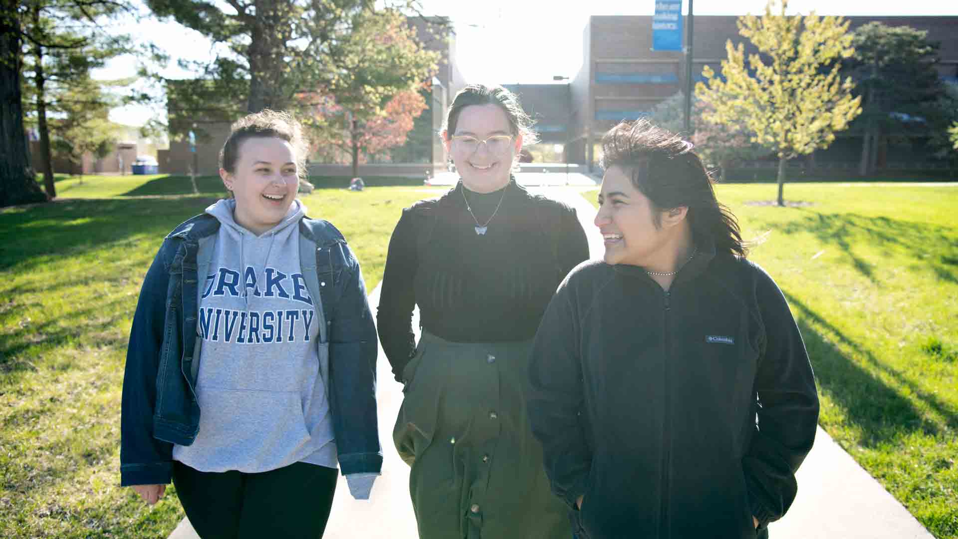 Three students smile while walking on campus