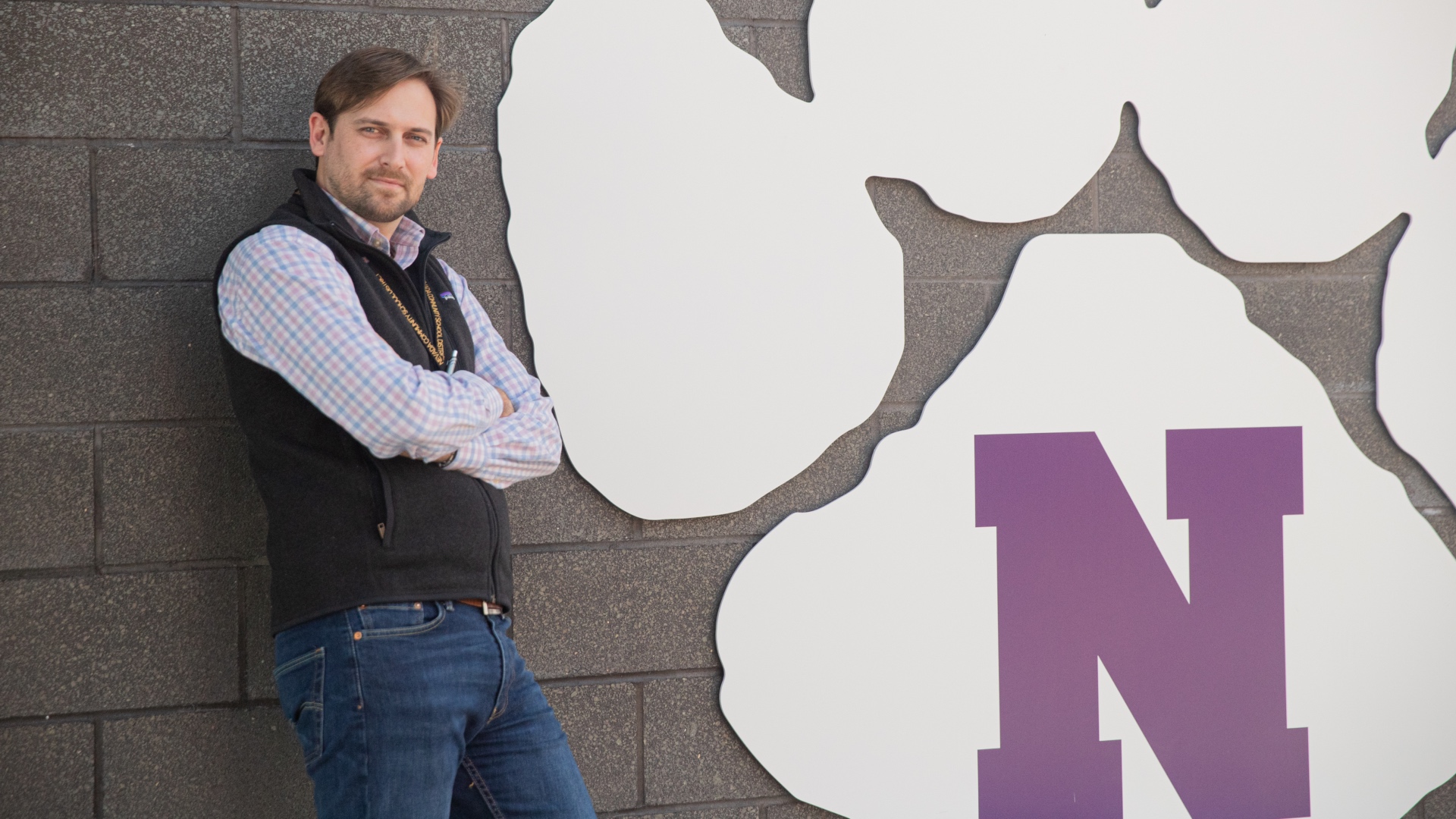 A principal leaning against his school's logo