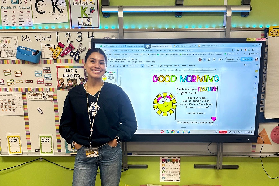 A student teacher smiling while standing in front of the whiteboard on her first day of student teaching