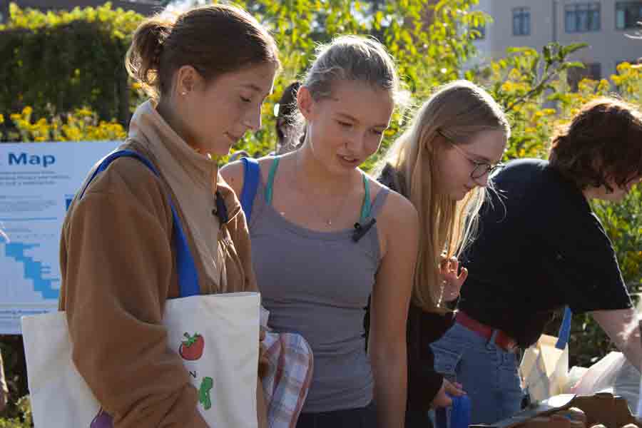 A group of students look at items on a table during a organization tabling event