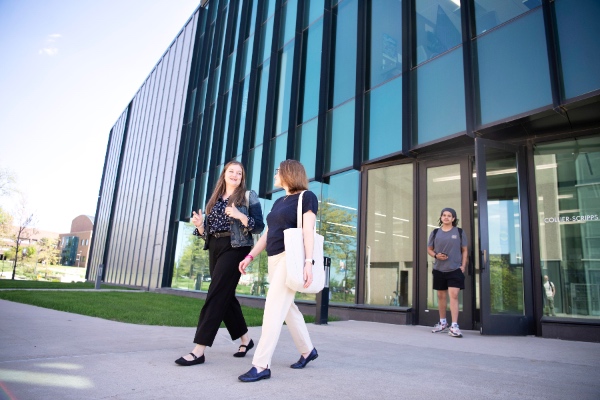 Two women walking out of Collier-Scripps talking and dressed business casual