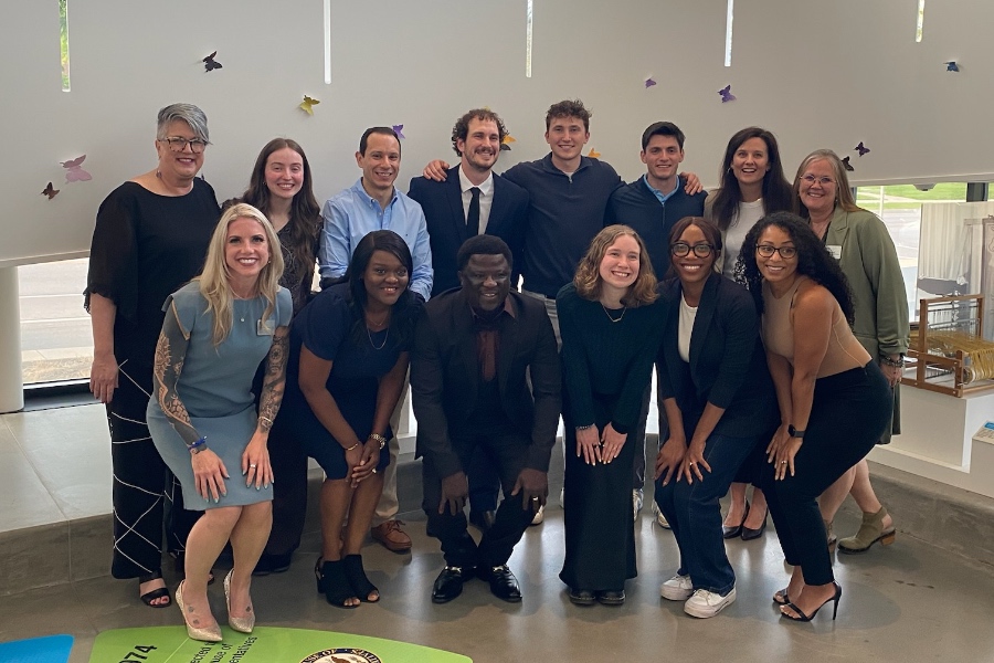 A cohort of capstone students smiling in a group after presenting