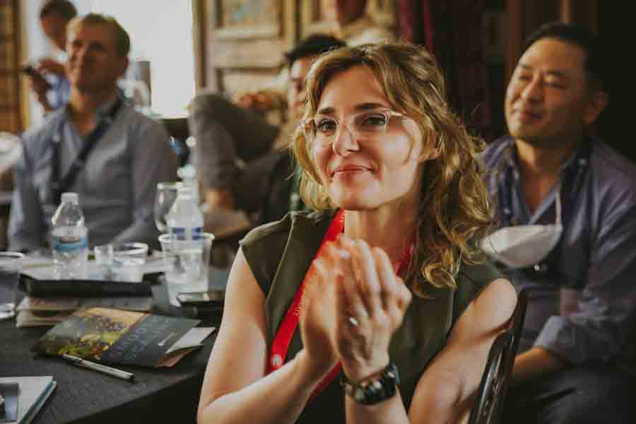 A student smiles and claps while sitting at a table during an event