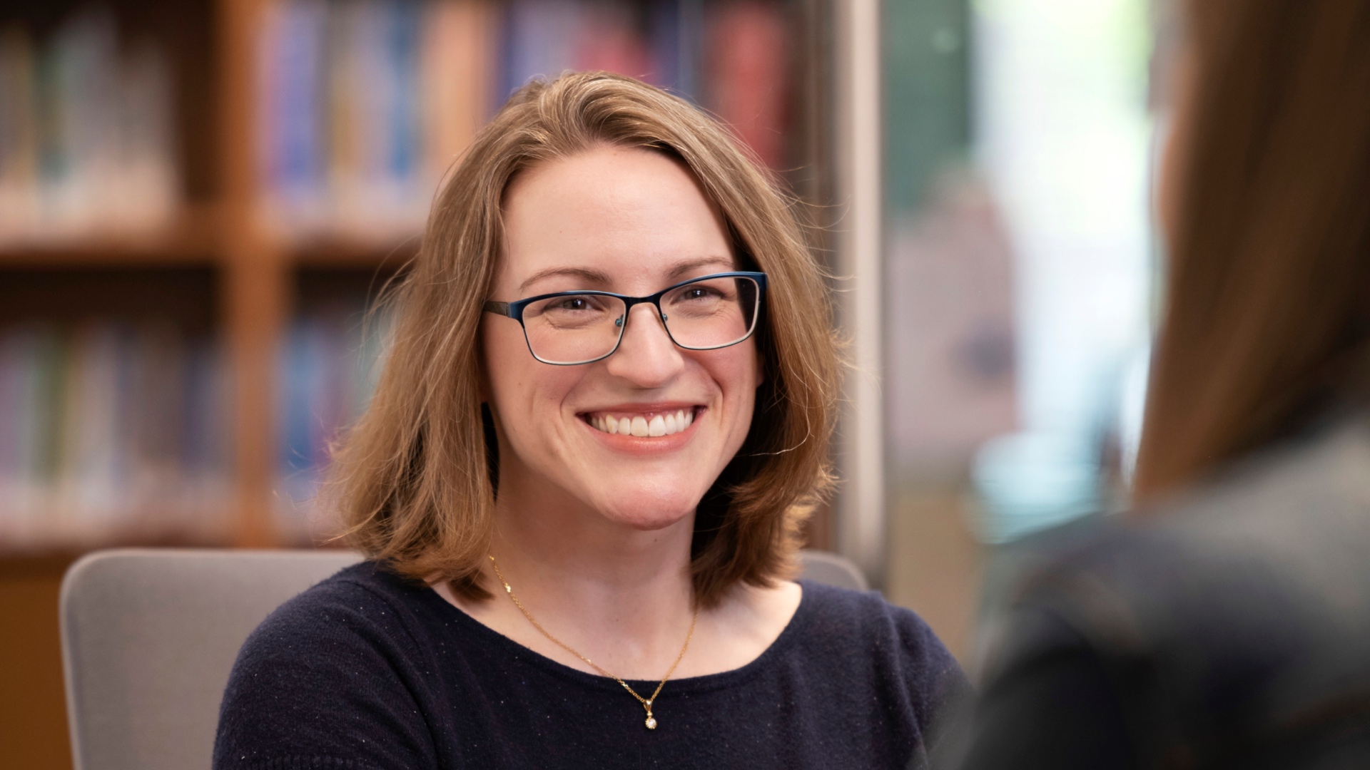 A doctoral student smiling while speaking to someone