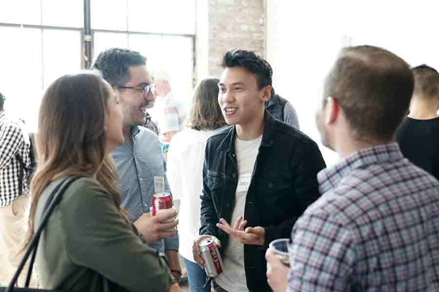 A group of students stand around talking and networking