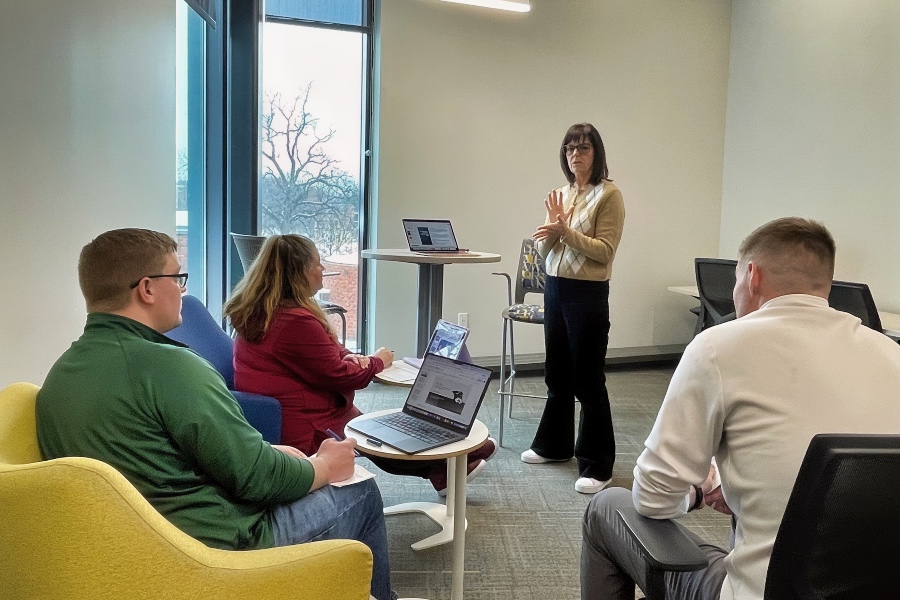 a student presenting to three other students 