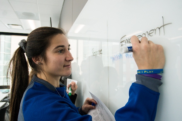 A student writing he word engagement on a whiteboard