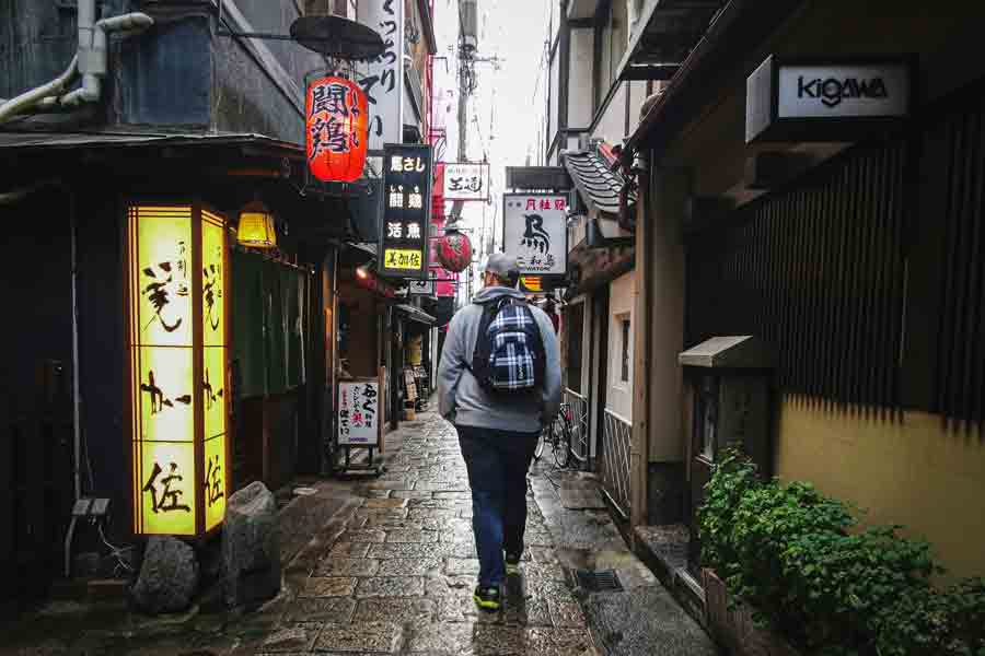 A student wearing a backpack walks down a street in Japan
