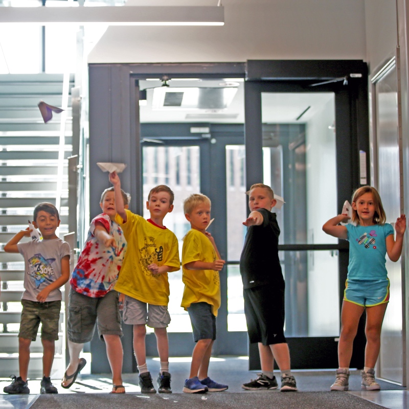 stem camp kids throwing paper airplanes toward the viewer