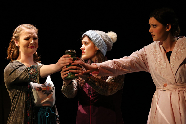 Three students on stage in costume during a theatre performance