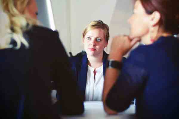 A student in business attire looks at two others sitting across the table