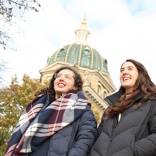 Two female students standing in front of the Iowa State Capitol building in Des Moines.