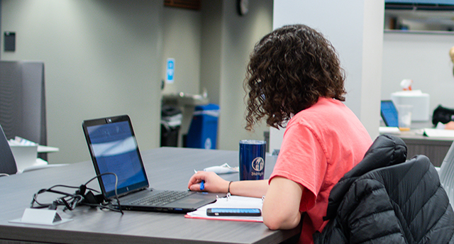Photo of a student working in Cowles Library on her laptop
