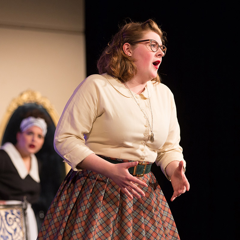 A Drake University student in costume performing on the theater stage