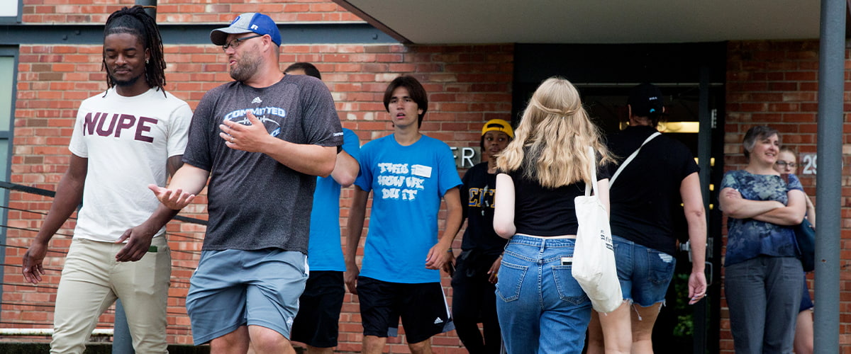A group of Drake University students and parents walking in and out of the front doors of a residence hall during move in day