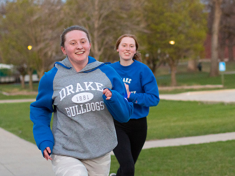 Two students running together wearing Drake Bulldogs sweatshirts