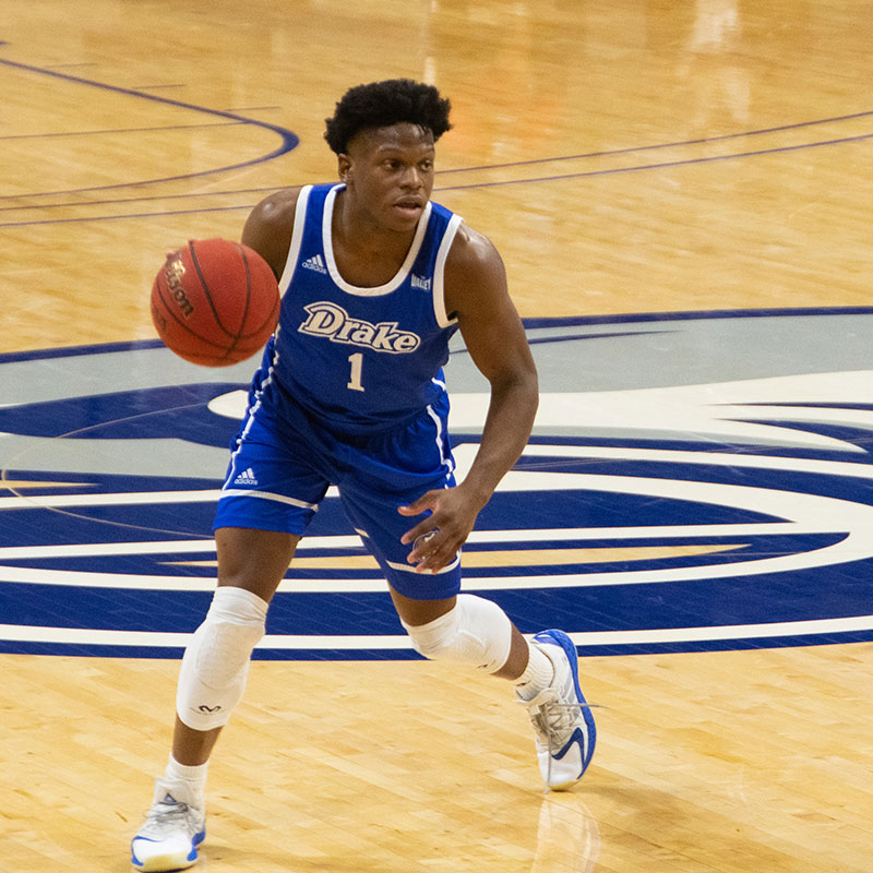 Drake University basketball player on the court dribbling a basketball during a game