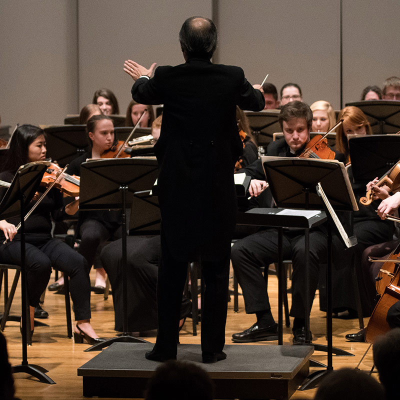 A conductor leading an orchestra of students