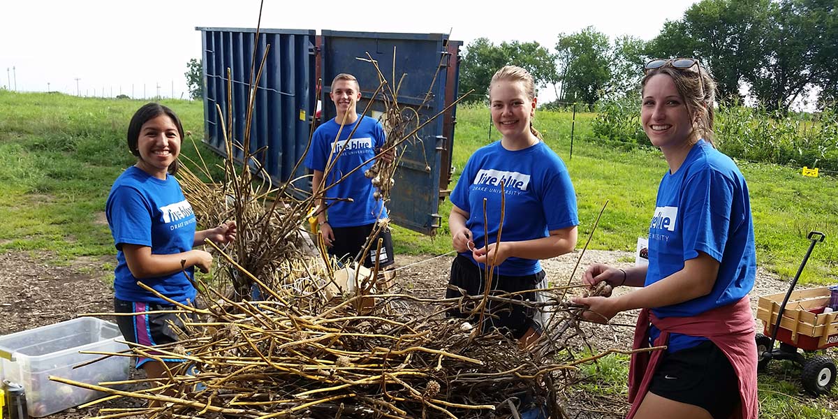 Four students volunteering as part of the student service and leadership training programs offered at Drake