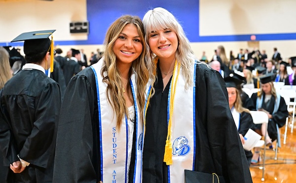 Students standing in the Knapp Center before Commencement with their regalia on